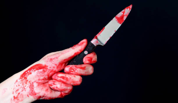 Bloody hand holding a bloody knife on a black background, Halloween concept